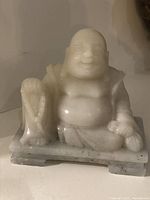 White jade vintage Happy Buddha statue, seated pose, holding sack, mounted on rectangular jade base.