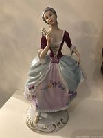 Front view of the porcelain lady figurine holding a fan, showing detailed dress and base.