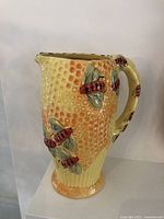 Front and side view of ceramic pitcher with honeycomb texture and bees.