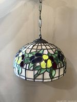 Side profile view of the hanging stained glass ceiling lamp showing the floral stained glass with green leaves, yellow, purple, and burgundy flowers.