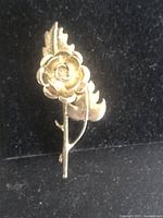 Front view of the sterling silver rose brooch showing the flower and leaves on black background.