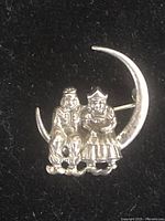 Front view of the vintage sterling silver brooch showing two children sitting on a crescent moon.