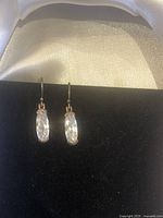 Front view of earrings showing clear faceted oval crystals set in sterling silver hooks, displayed on black velvet.