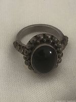 Close-up of the sterling silver ring with visible black onyx stone and detailed bezel.