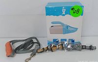 Cat litter scoop in box with grey leash and two bowtie collars in front.