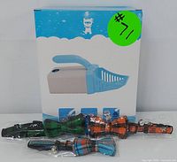 Boxed cat litter scoop alongside three plaid bowtie pet collars in green, orange, and blue.
