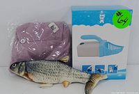 Brand-new folded purple apparel, plush fish toy, and boxed cat litter scoop