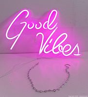 LED neon sign spelling 'Good Vibes' lit up in pink, showing the script style and glow of the sign.