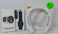 Soudorv smart watch fitness tracker with navy blue band and box next to white rechargeable neck fan in packaging.