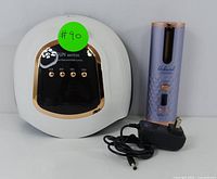 Photo showing both the white SUN Mate50 UV nail lamp and the purple Unbound cordless auto curler with its charger adapter.