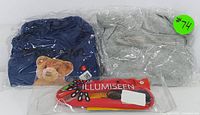 Photo showing two pet apparel pieces in plastic bags: navy blue 2XL size and light gray 3XL size, plus the Illumiseen branded red LED rechargeable dog collar in packaging.