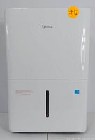 Front view of the white Midea dehumidifier with a water level window and Midea logo on top center.