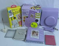 Full lot display showing lavender leather instant camera case, lavender photo album, polka dot patterned albums and photo accessories, in packaging and loose.