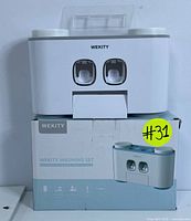 Front view of WEKITY wall-mounted bathroom organizer on its original box showing dual dispensers and overall design.