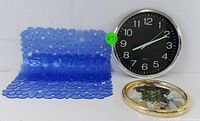 Wall clock, picture frame, and one bath mat shown upright against white background