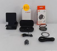 Full view of all included items: black wireless earbuds with charging case and accessories, boxed MagSafe wireless charger with cable, black adjustable phone stand.