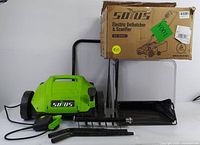Full lot including main green and black electric dethatcher scarifier unit, detachable handles, black fabric collection bag, and original box.