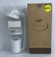 White LED hydroponic system in clear packaging alongside its original box labeled 'LED Hydroponic System' with color options black and white.
