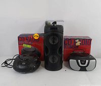 Three Proscan audio devices: one Bluetooth speaker and two CD radio boomboxes with original packaging visible behind each device