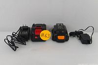 Two rechargeable power tool battery packs with matching chargers displayed side by side on a white surface.