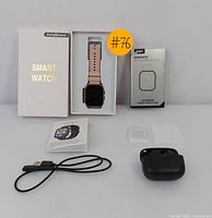 EarlySincere smartwatch in original box with rose gold band, ESR Armorite screen protector box, user manual, USB charging cable, and black wireless earbuds with charging case displayed on white surface.