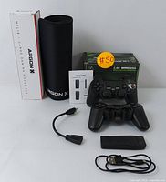 Photo of two wireless gaming controllers, USB wireless receiver, USB extension cable, instruction manual, and rolled Argon X Helix large gaming mouse pad with packaging box