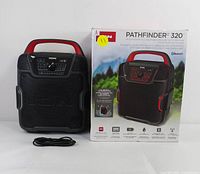 Front view showing the speaker, original box, and power cable laid out.