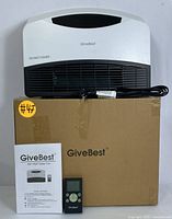 Front view of GiveBest electric heater sitting on its original box with remote control and user manual in front