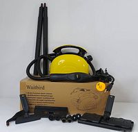 Full lot showing Waitbird steam cleaner unit, power cord, flexible hose and handle, two extension wands, various nozzle and brush accessories, all arranged on cardboard box with printed product info.