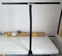 Full view of assembled office screen lamp with clamp base on table, packaging box in background.