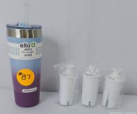 Photo of Ello tumbler with silicone bumper, clear lid, and straw plus three sealed water filters in plastic wrap beside it.