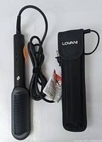 LOVANI heated hair straightener with comb-like plate and attached power cord, next to a black LOVANI protective carrying case with flap closure showing branding.