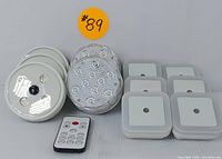 View showing assortment of two types of round LED puck lights and black remote control.