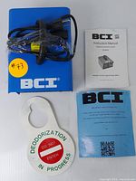 BCI UltraMAX ozone deodorizer power cable, instruction manual, safety guide booklet, and 'Deodorization in Progress' warning sign.