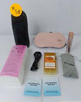 Photo showing the full beauty set including the black electric wax warmer, wax refill, two blue after-waxing wipes, USB cable, pink eye massager, instruction manual, and rose gold facial trimmer with pouch and two gold heads.