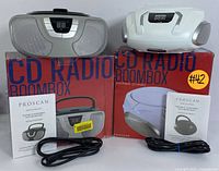 Two Proscan portable CD boomboxes with their original boxes, power cords, and instruction manuals.