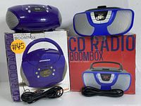Two portable CD radio boomboxes shown with original packaging and power cords
