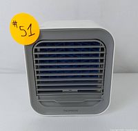 Front view of the Thomson mini portable air conditioner showing front grille with blue fan blades behind gray louvers and Thomson branding on bottom front edge.