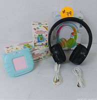 Photo shows black wireless stereo headphones with USB charging and audio cables, blue kids' educational learning tablet, and flashcard box.