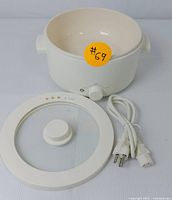 White electric cooker ceramic pot, glass lid, power cord, and temperature knob shown disassembled for display.