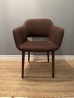 Front view of brown Kvadrat fabric MCM style Torre 1961 armchair with curved backrest and armrests on wooden legs.