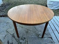 Round teak table top unextended, straight tapered legs visible