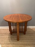 Front view of the Mission oak round table showing the circular tabletop and slatted vertical supports beneath.