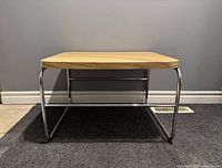 Front view of the vintage Artopex side table showing wood laminate top and chrome tubular metal frame