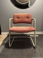 Front view of chair showing red upholstered seat and back with light gray tubular frame