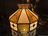 Close-up of the stained glass pendant lamp showing amber and cream glass panels with red diamond accents.