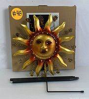 Metal sun-shaped garden light with LED lights and metal installation stake shown against a box with the number 48 sticker.