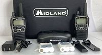 Photo showing two Midland X-Talker radios flanking a dual charging dock, AC power adapter, rechargeable battery packs, and accessories against a white background.