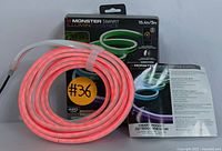 Photo showing the Monster Smart Illuminessence RGB Neon Light Strip coiled, glowing red, with original packaging and setup instructions visible.