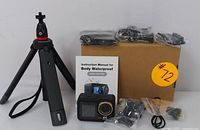 Camera with the tripod, mounting accessories, instruction manual, and box displayed on a white background.